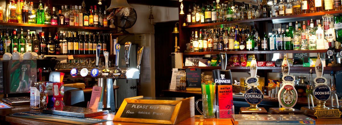 The bar, its pumps and back-bar shelves of bottles under warm light