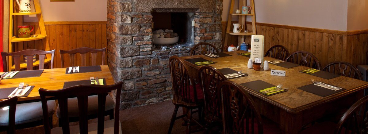 The dining room, tables laid beside a stone inglenook fireplace