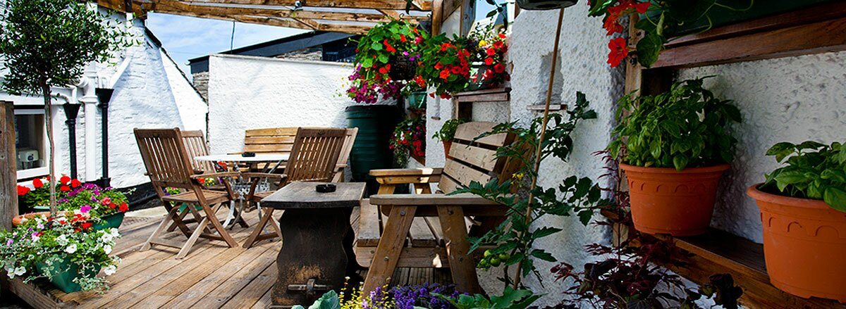 The walled courtyard garden, decked and full of pots, hanging baskets and climbing plants